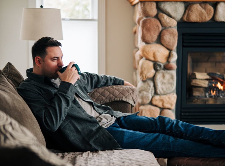 man sitting on couch in front of fireplace