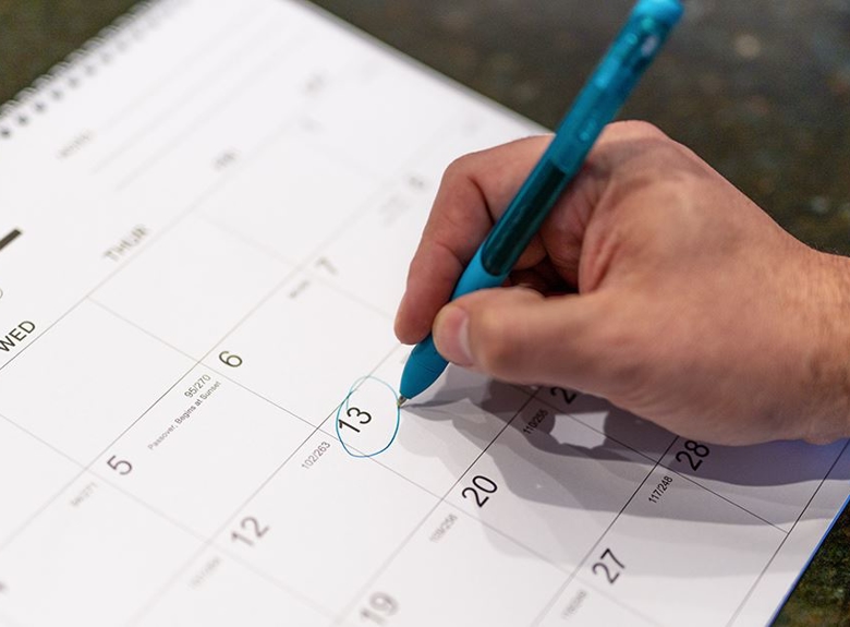 hand holding pen scheduling service on calendar